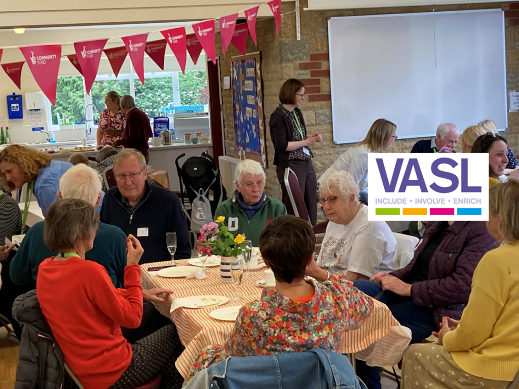 Volunteers seated at tables during cream tea.